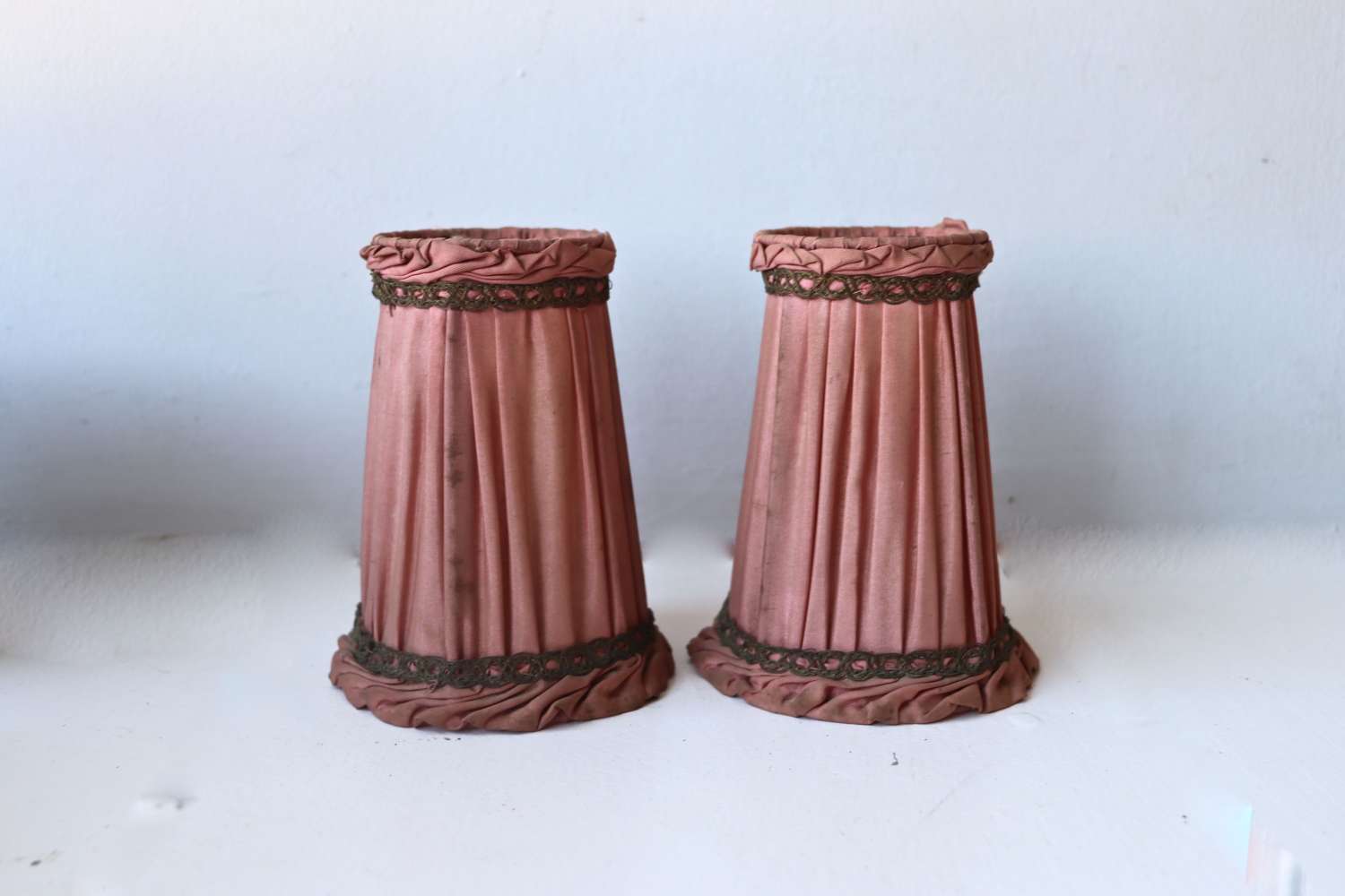 Pair of small salmon coloured pleated and metallic braided lampshades